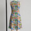 Animal Crossing sleeveless dress with all-over print of villagers Isabelle KK Slider and island characters in colourful print, flowy knee length front view on mannequin