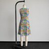 Animal Crossing sleeveless dress with all-over print of villagers Isabelle KK Slider and island characters in colourful print, flowy knee length front view on mannequin