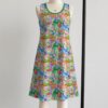 Animal Crossing sleeveless dress with all-over print of villagers Isabelle KK Slider and island characters in colourful print, flowy knee length front view on mannequin