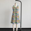 Animal Crossing sleeveless dress with all-over print of villagers Isabelle KK Slider and island characters in colourful print, flowy knee length front view on mannequin