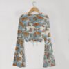 Monarch butterfly print mesh crop top with bell sleeves and tie front bow, all-over butterfly and cloud print on blue grey background, women's fit front view on hanger