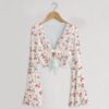 Cherry print mesh crop top with bell sleeves and tie front bow, all-over red cherry and heart print on white, women's fit front view on hanger