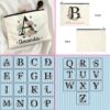 Personalised floral initial zipper pouch with letter A and name Amanda in script font surrounded by pink and white daisy print on cream canvas makeup bag