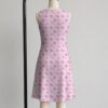 Pink sakura cherry blossom sleeveless dress with all-over pink floral print and sparkle details on pale pink background, flowy knee length front view on mannequin