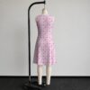 Pink sakura cherry blossom sleeveless dress with all-over pink floral print and sparkle details on pale pink background, flowy knee length front view on mannequin