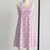 Pink sakura cherry blossom sleeveless dress with all-over pink floral print and sparkle details on pale pink background, flowy knee length front view on mannequin