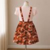 Orange and brown camo skirt overalls dress with adjustable straps and midi length skirt, all-over camouflage print