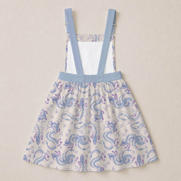 Haku dragon skirt overalls dress with all-over print of river spirit dragon in blue and lavender on cream background, adjustable straps