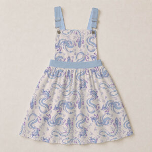 haku-beige-overalls-dress-fr Haku dragon skirt overalls dress with all-over print of river spirit dragon in blue and lavender on cream background, adjustable straps