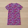 kpophuntrix-girls-tee-dress-fr Kpop Demon Hunters girls' t-shirt dress with all-over print featuring chibi-style Rumi, Zoey, and Mira characters with rainbows, microphones, and colorful accents on a purple-pink background